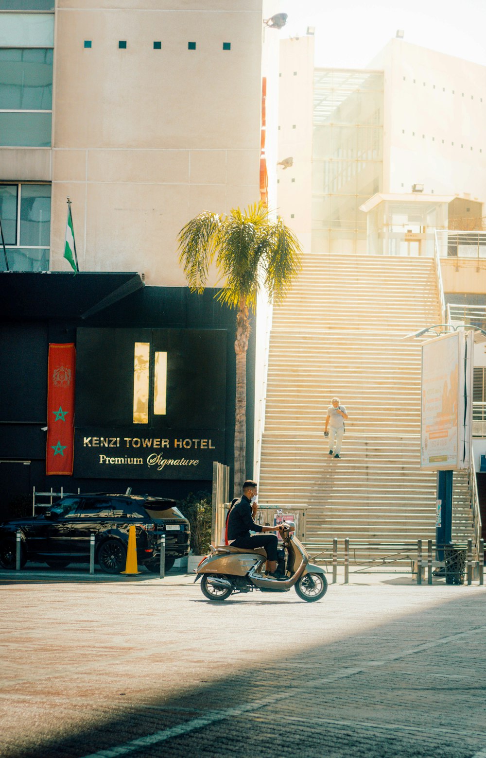 a man riding a motorcycle down a street next to a tall building