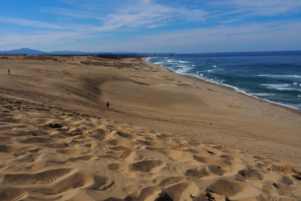 a sandy beach with waves coming in from the ocean