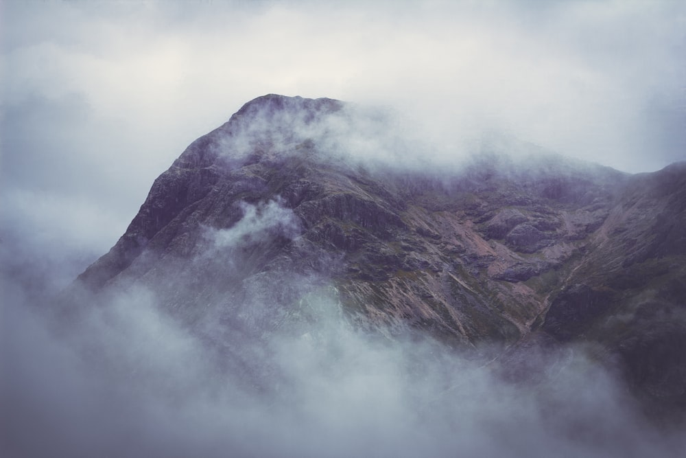 a mountain covered in fog and clouds on a cloudy day