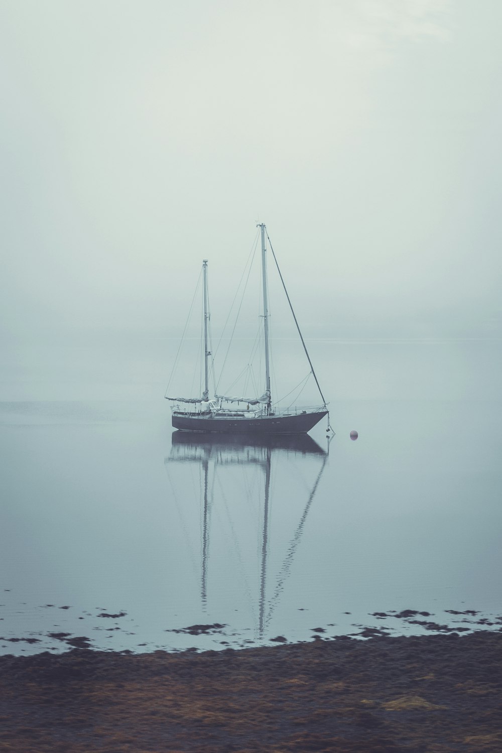 a sailboat in the water on a foggy day