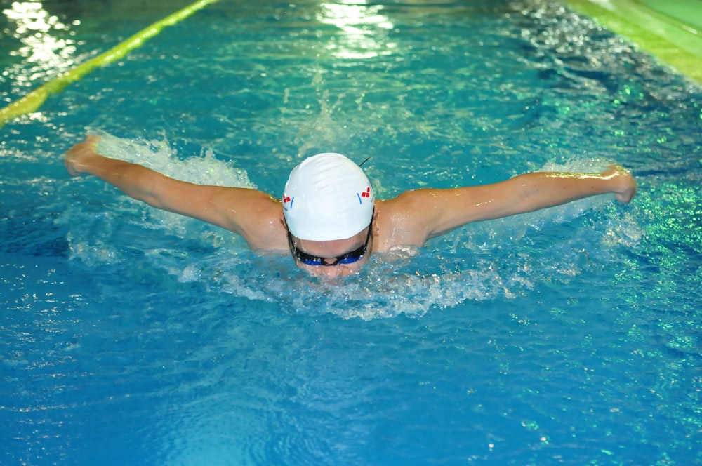 a woman swimming in a pool wearing a white hat