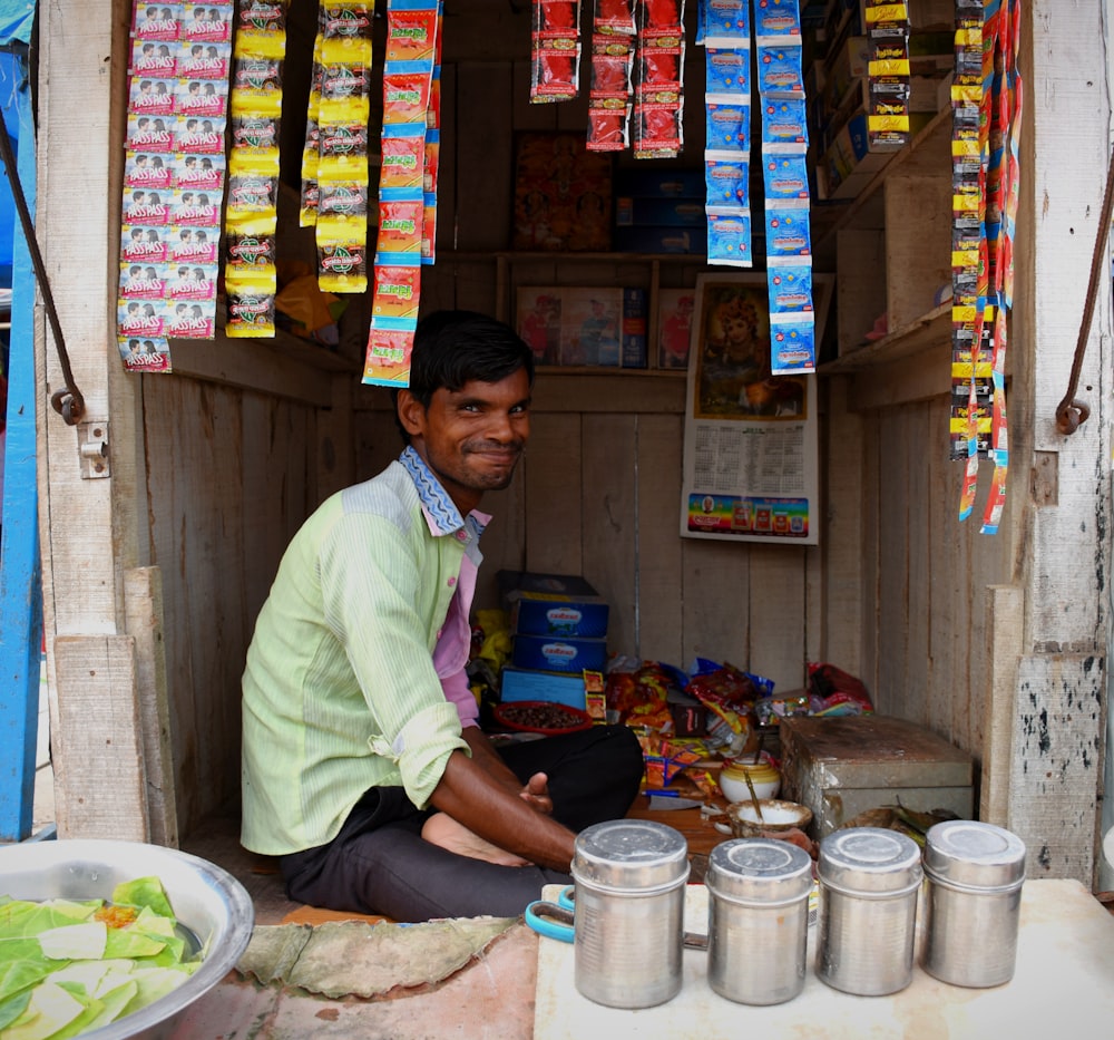a man sitting in the doorway of a store selling food