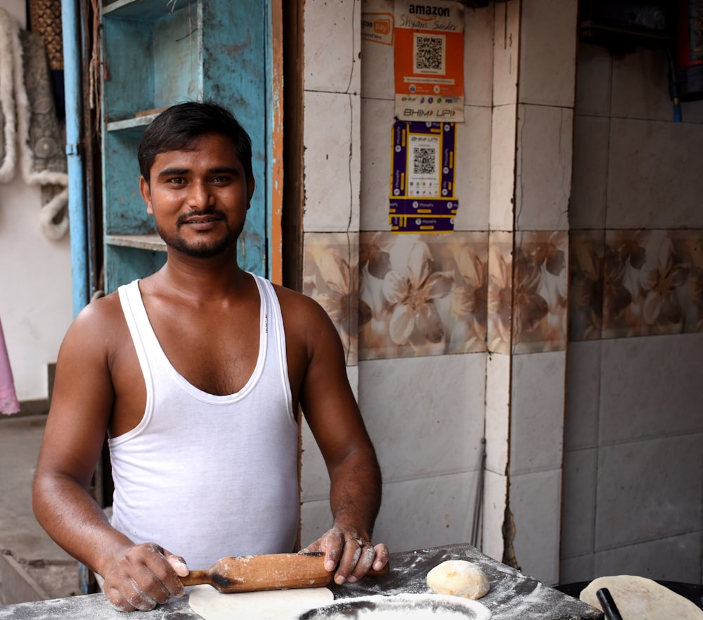 a man in a tank top is making bread