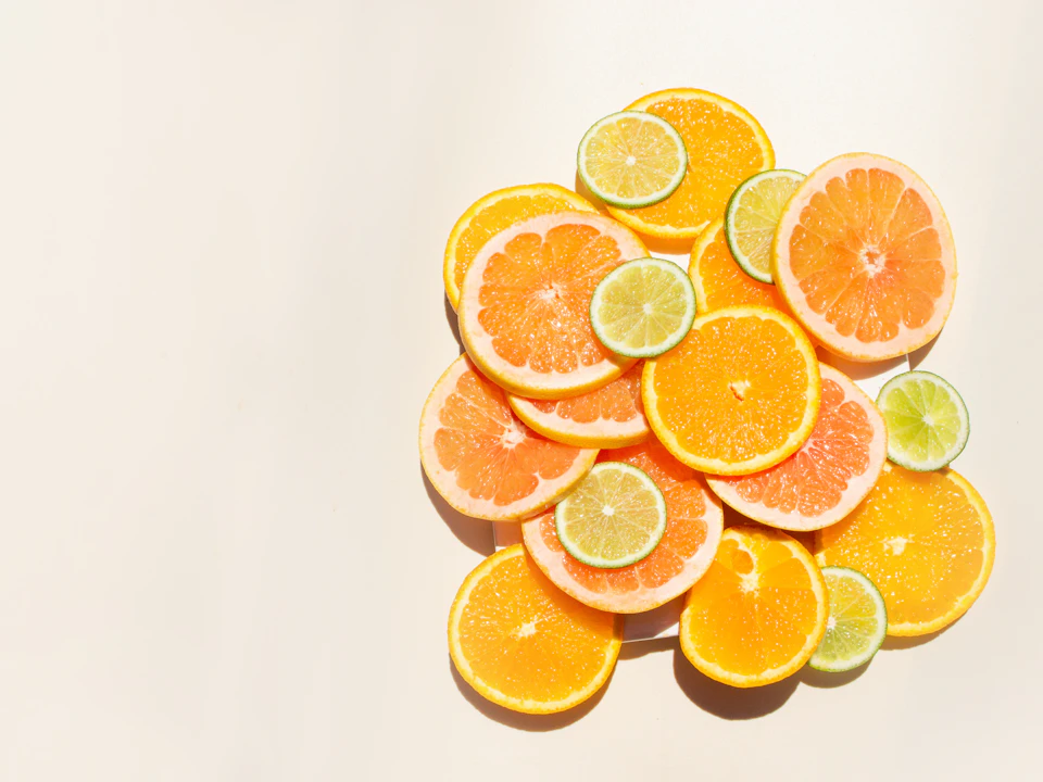 Vibrant citrus fruits arranged on a white background, showcasing sliced oranges and halved limes