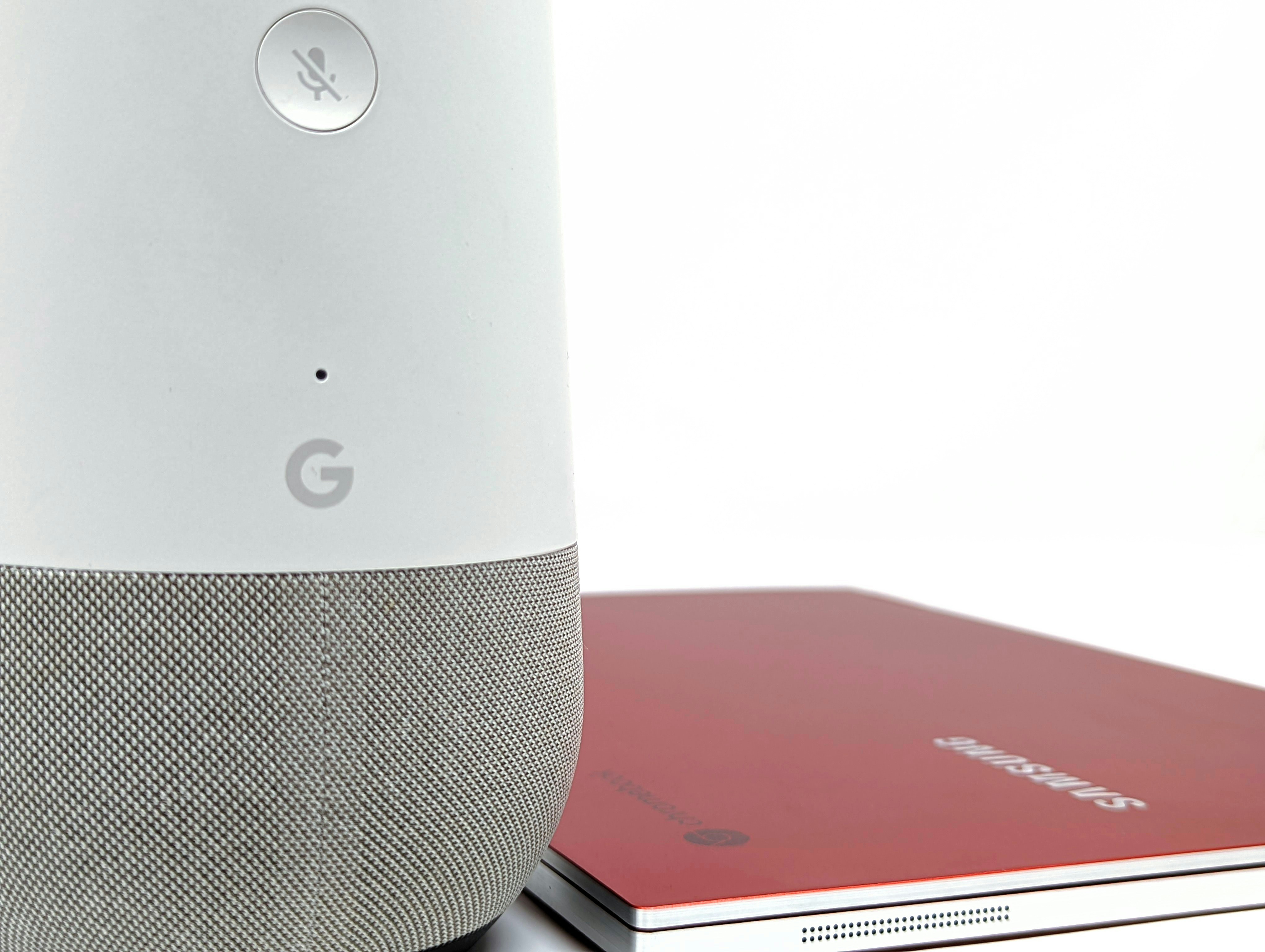 a white and red smart speaker next to a red laptop