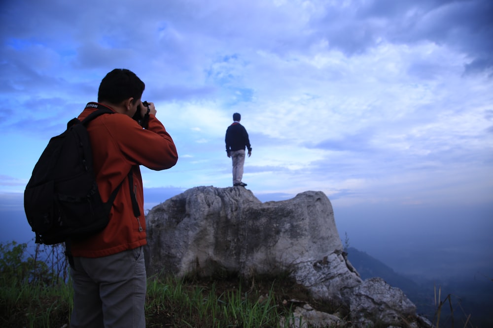 a man standing on top of a rock while talking on a cell phone