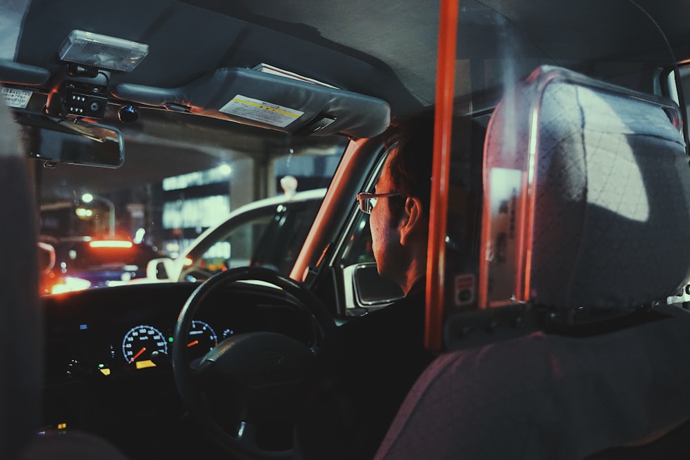 a man driving a car with luggage on the back of it