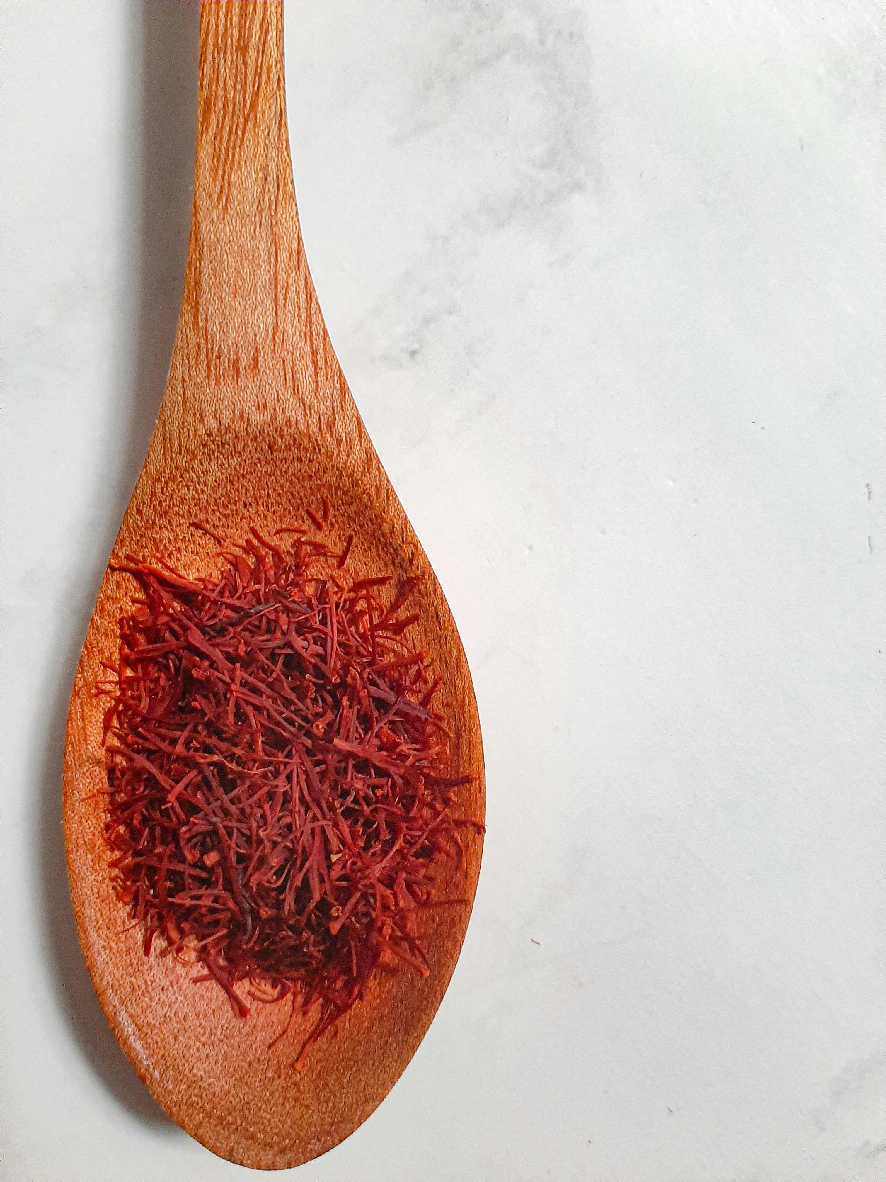 Chef in white apron working with saffron threads in a bright professional kitchen, warm natural light