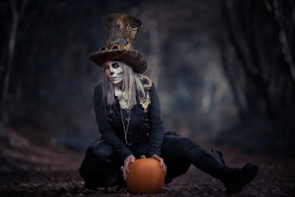 a woman dressed in a skeleton costume sitting on a pumpkin