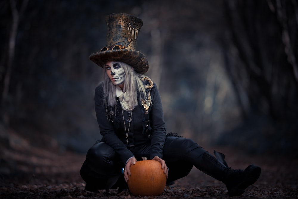 a woman dressed in a skeleton costume sitting on a pumpkin