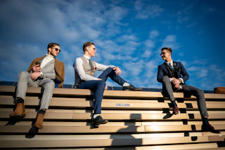 three men sitting on the bleachers of a stadium