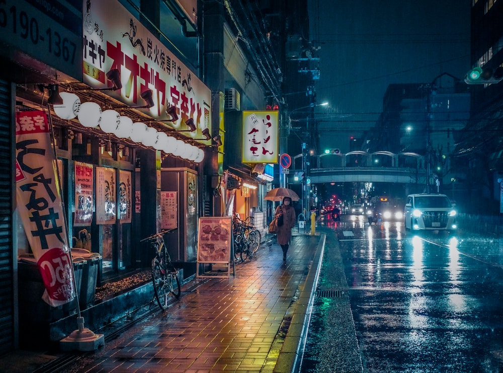 a city street at night with people walking on the sidewalk