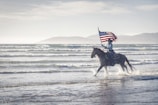 a man riding a horse with an american flag on its back