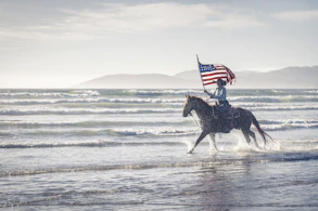a man riding a horse with an american flag on its back