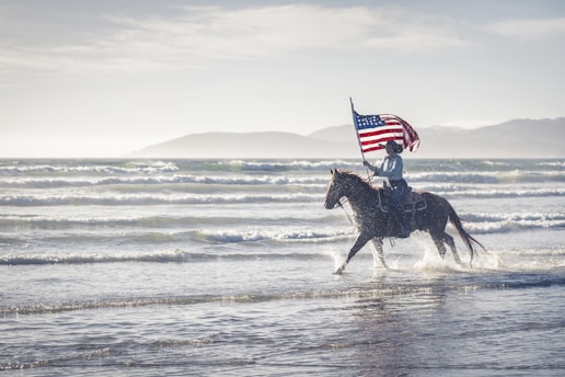 a man riding a horse with an american flag on its back