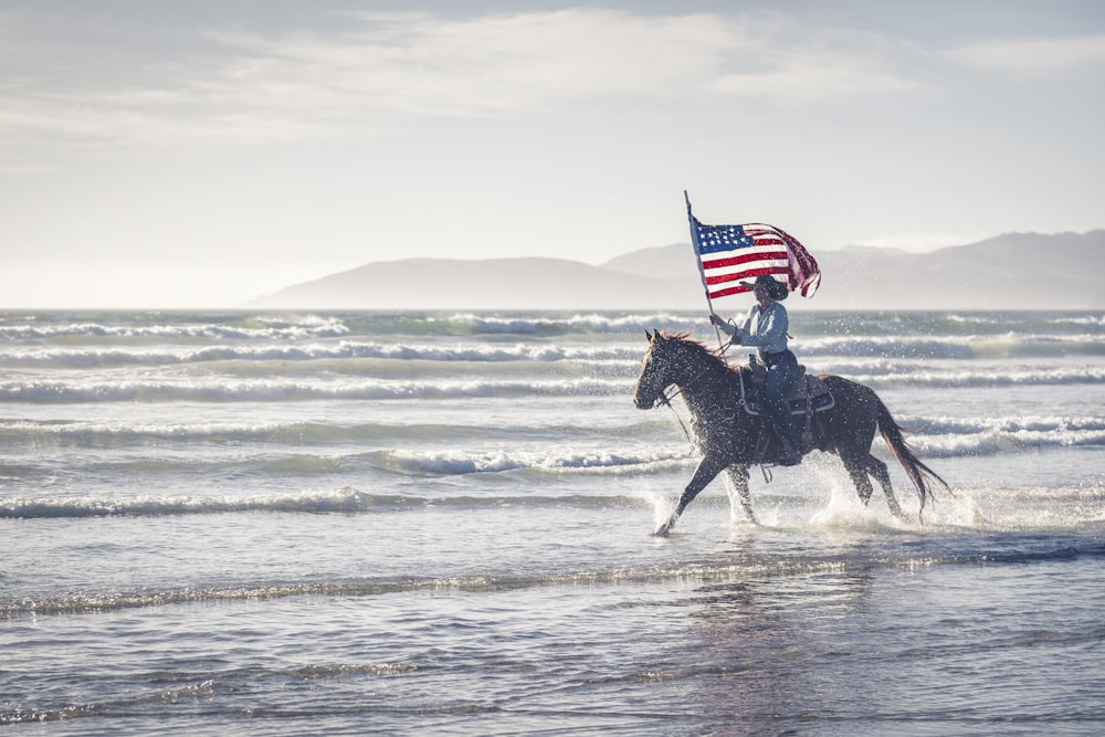 アメリカ国旗を背負った馬に乗る男