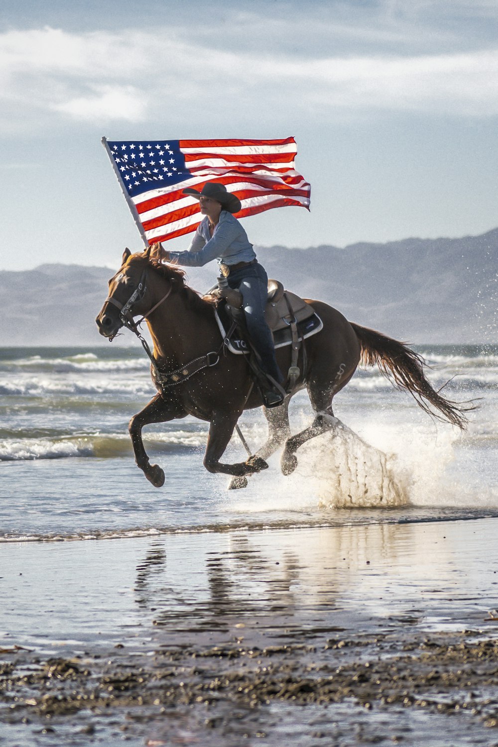 uma pessoa montando um cavalo com uma bandeira americana nas costas