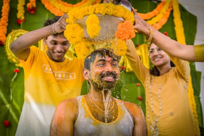 a group of people standing around a man covered in orange and yellow flowers