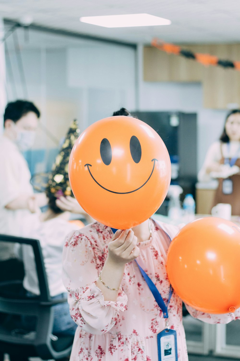 a woman holding two balloons with a smiley face on it