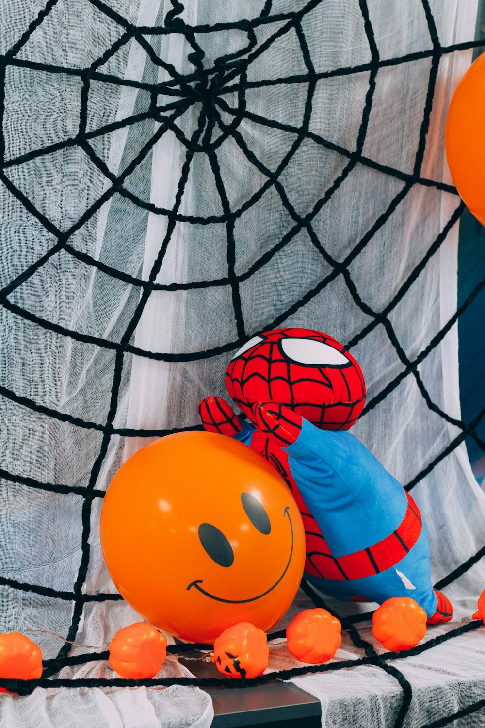 a spiderman balloon sitting on top of an orange ball