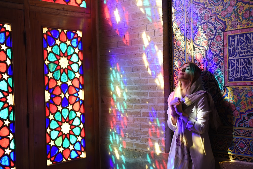 a woman standing in front of a colorful stained glass window