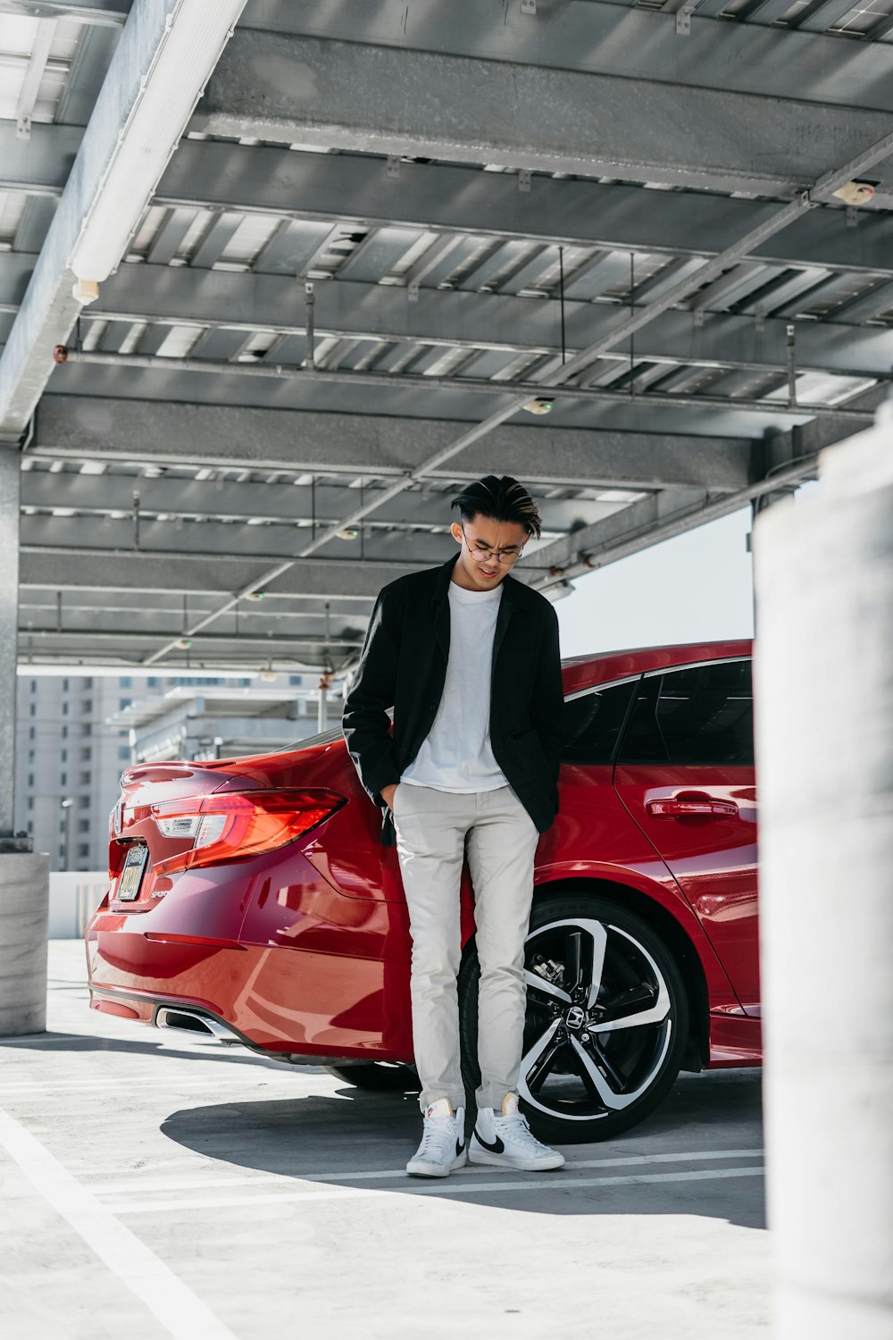 a man standing next to a red car
