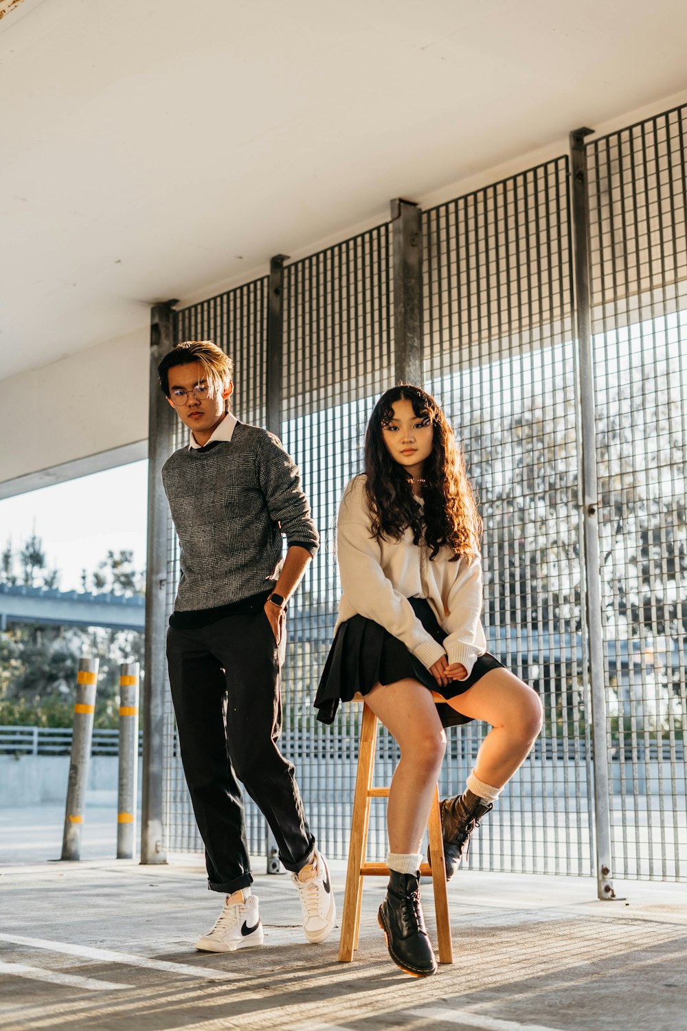 a man standing next to a woman sitting on a stool