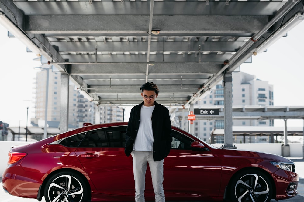 a man standing next to a red car