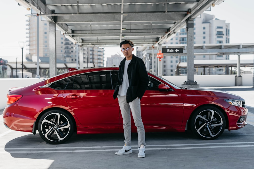 a man standing next to a red car