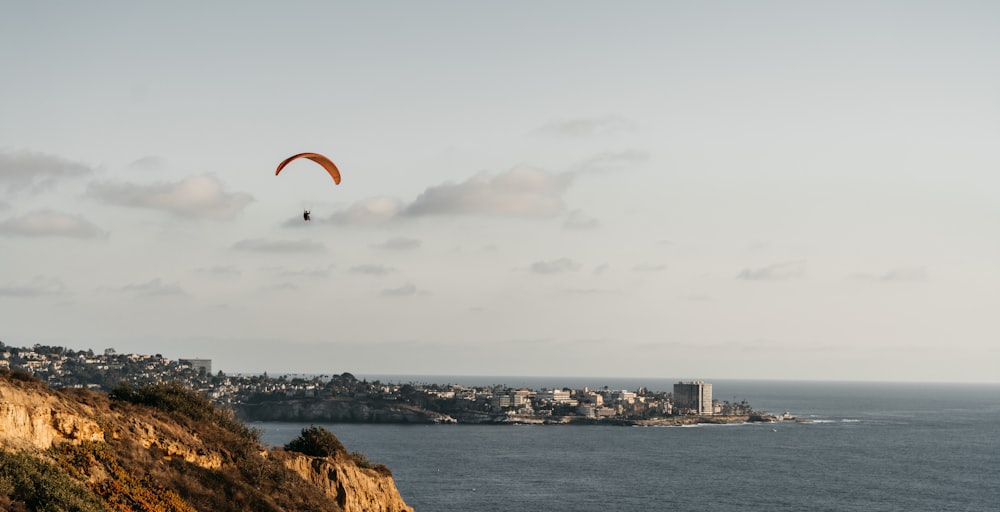 a paraglider is flying over a city on a cliff