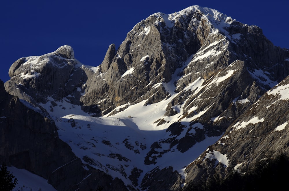 a large mountain covered in snow under a blue sky