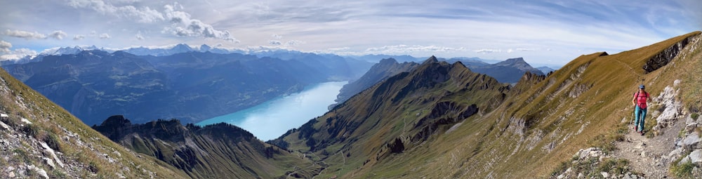 a man standing on top of a mountain next to a lake