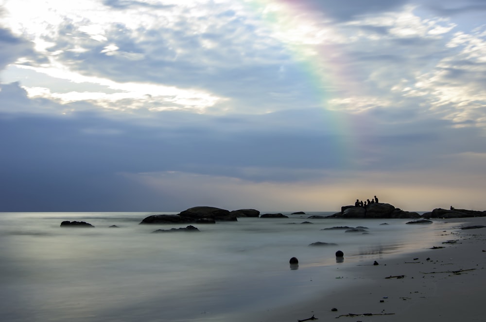 a rainbow shines in the sky over a beach