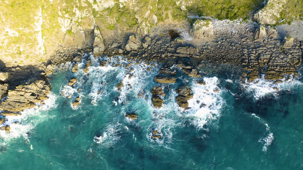 an aerial view of the ocean and rocks