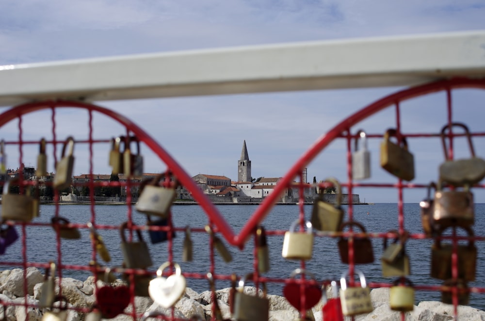 many padlocks are attached to a fence near a body of water