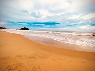 a sandy beach with waves coming in to shore