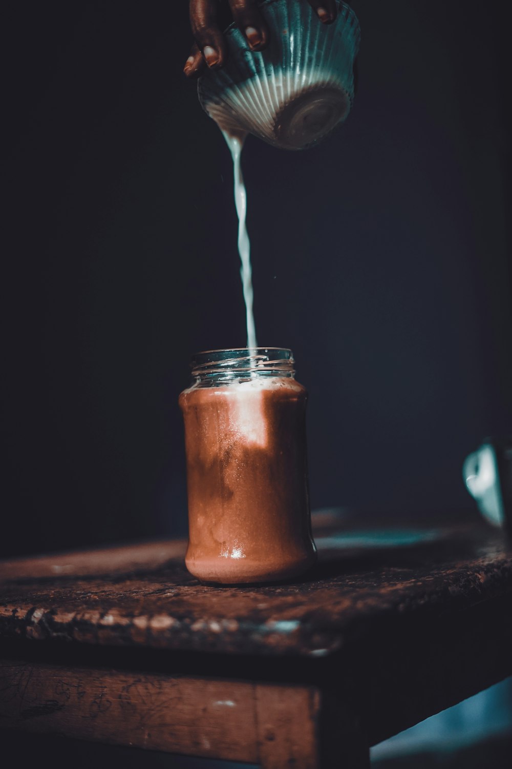 a person is pouring chocolate into a jar