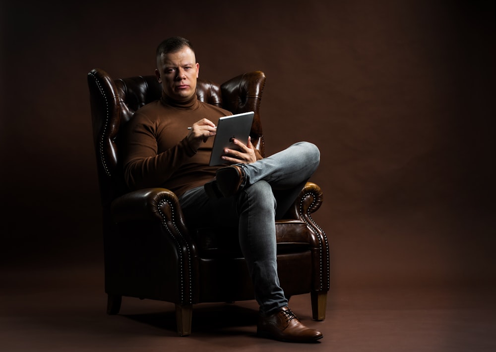Ein Mann sitzt auf einem Stuhl und hält ein Tablet in der Hand