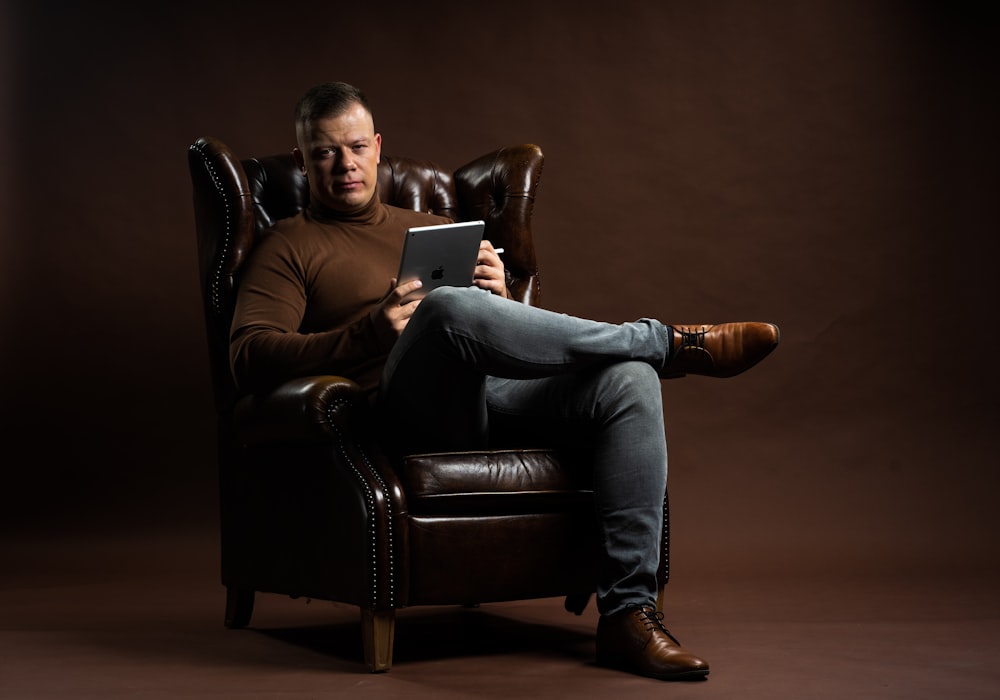 a man sitting in a chair holding a tablet