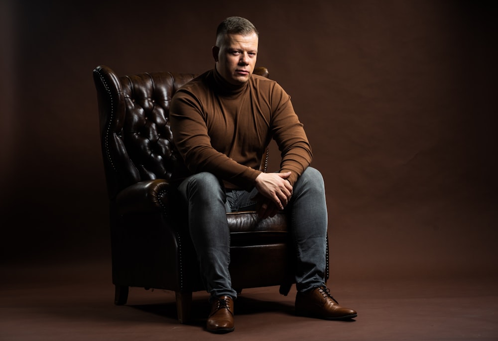a man in a brown sweater is sitting on a leather chair