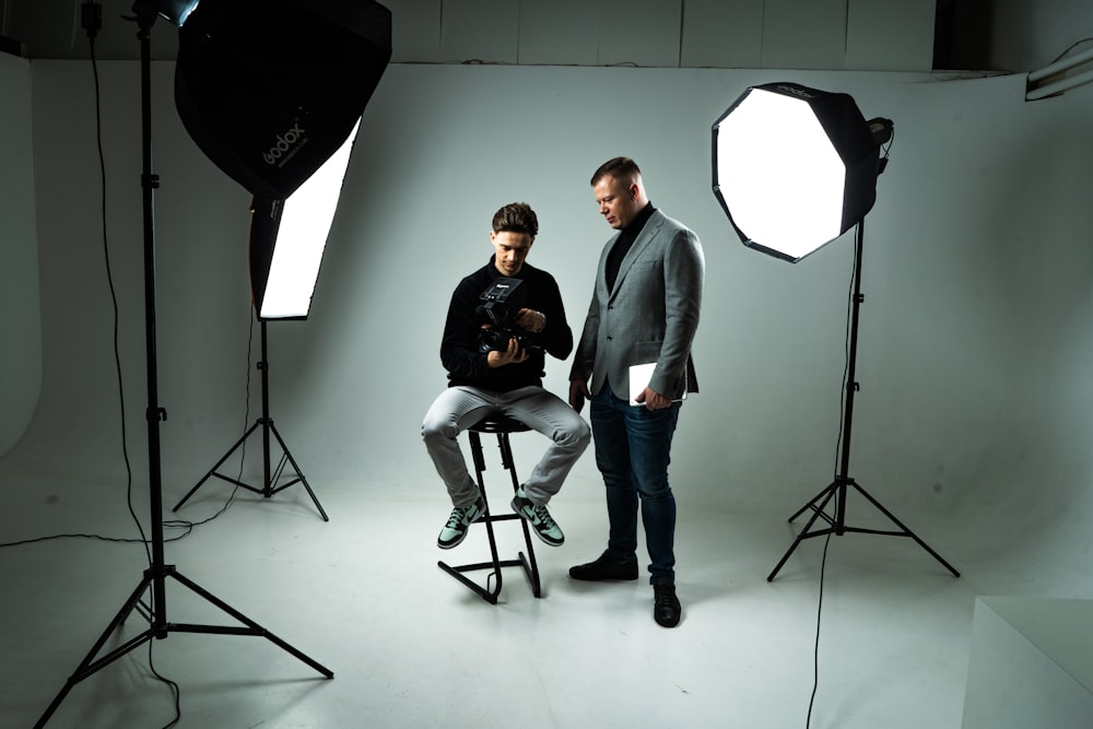 a couple of men standing in front of a camera