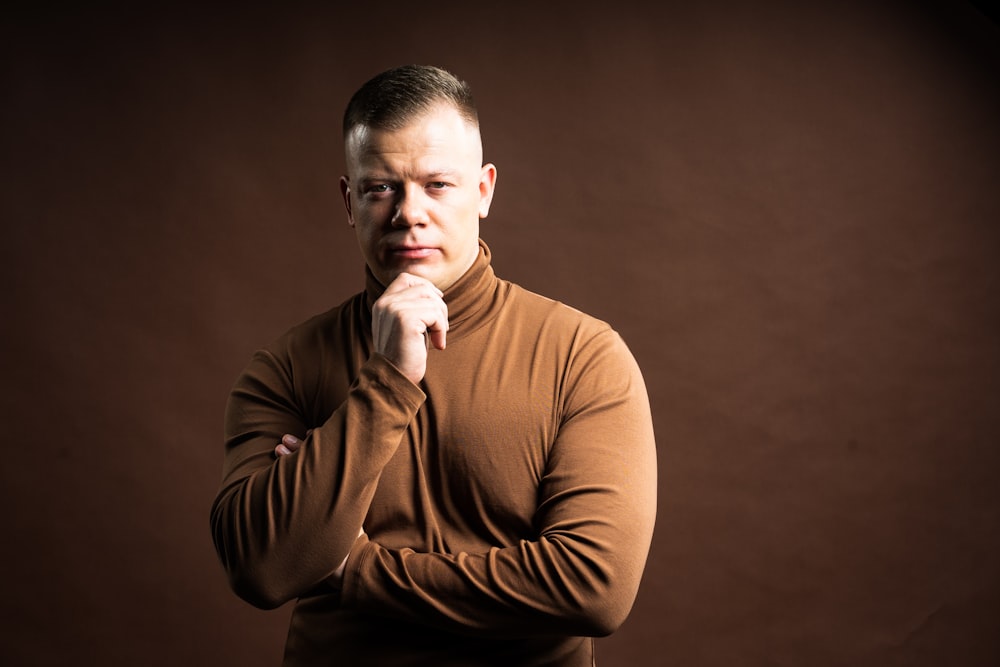 a man in a brown shirt is posing for a picture