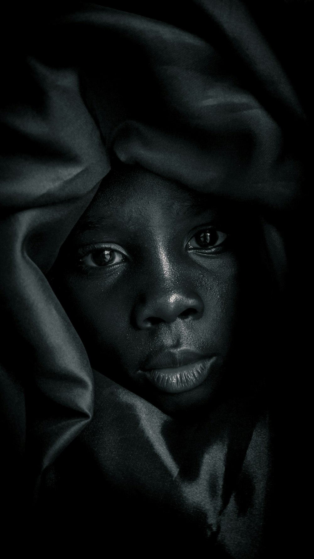 Una foto in bianco e nero di una donna con una coperta sopra la testa