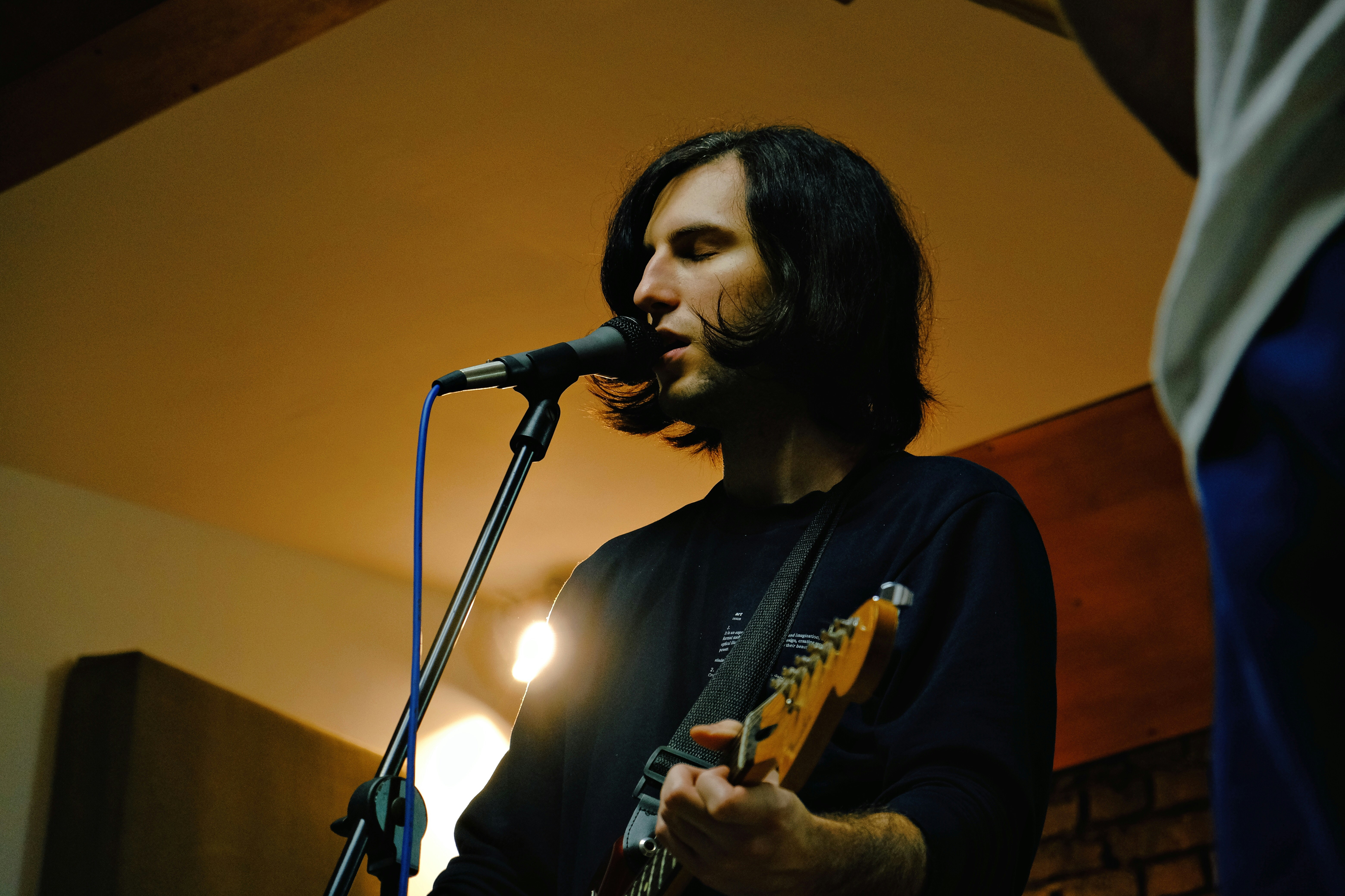 a man playing a guitar in front of a microphone