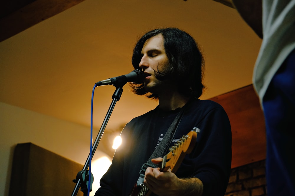 a man playing a guitar in front of a microphone