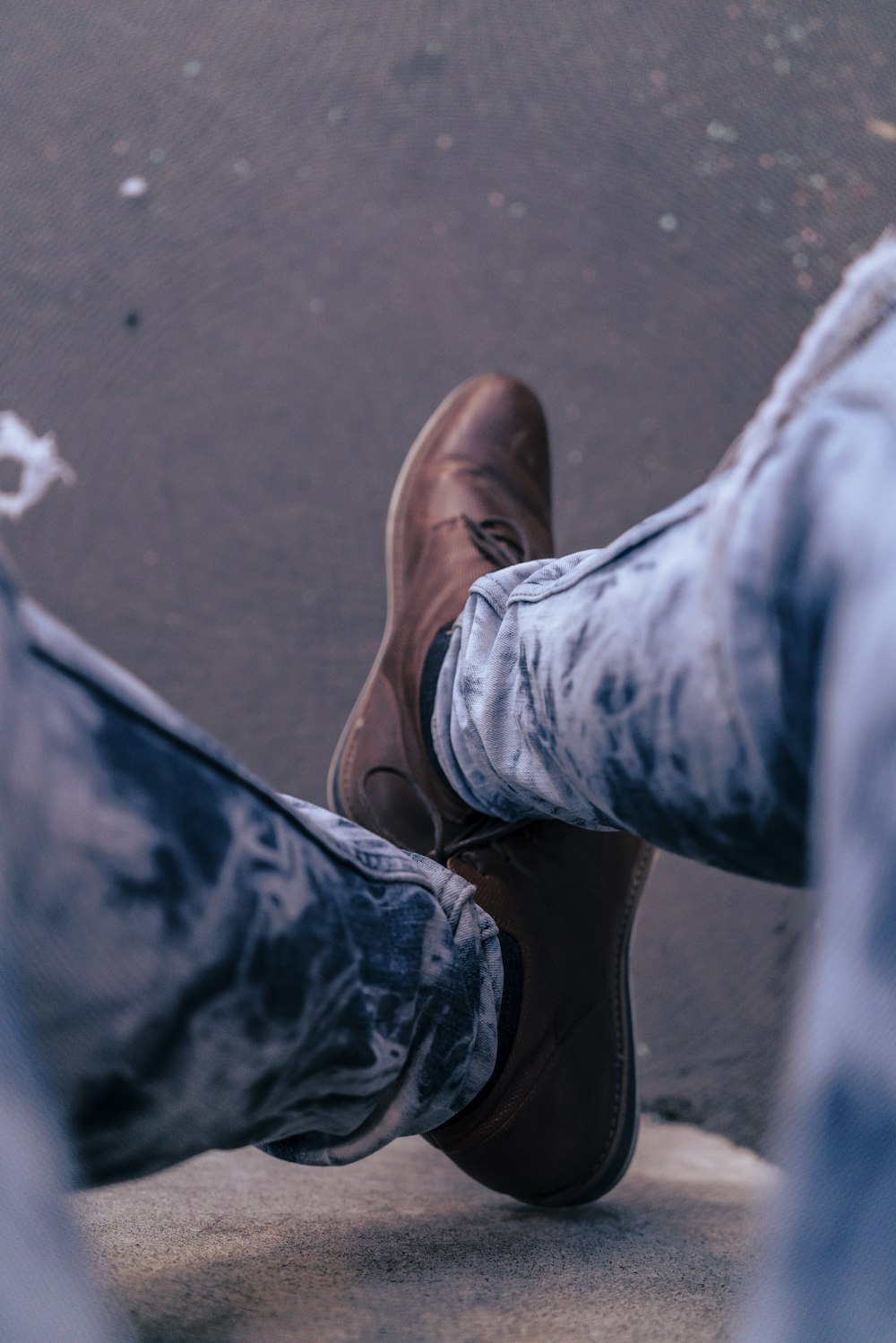 a person wearing brown shoes standing on a sidewalk