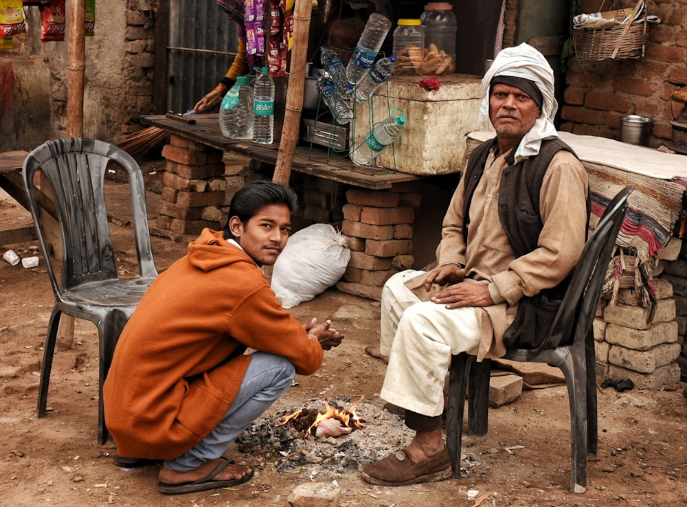 a man sitting on a chair next to another man