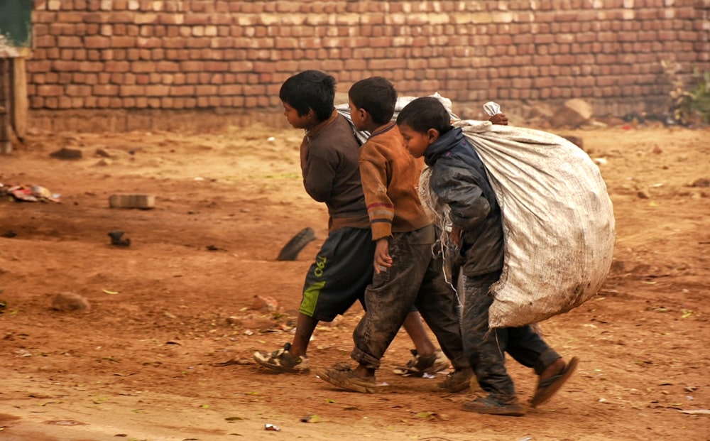 a group of young boys walking down a dirt road