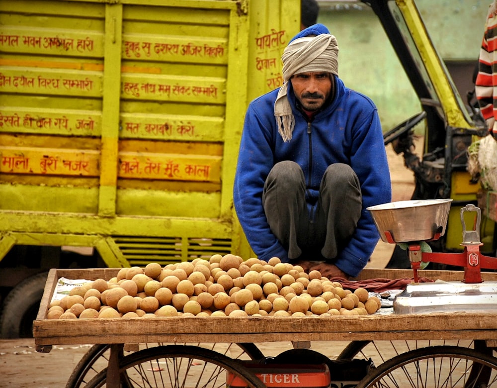 a man sitting on a cart filled with potatoes