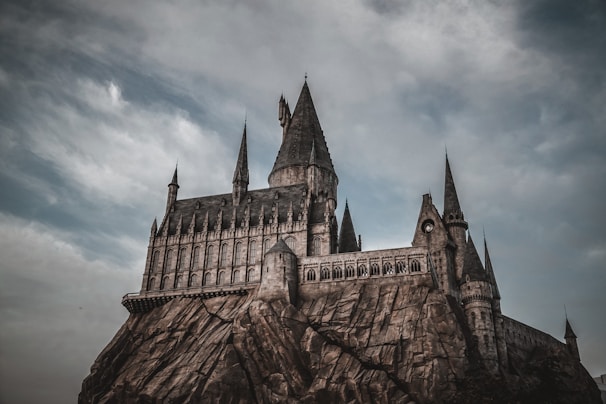 A striking black-and-white photo of a misty castle perched on a rugged cliff under a brooding sky.